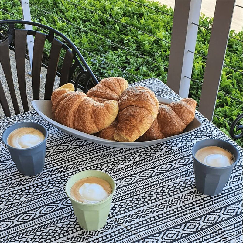 Bamboo platter in leaf shape - Colour Stone, holding 5 croissants.  also on a table with bamboo latte cups in charcoal and mint, sitting on a charcoal and white table cloth